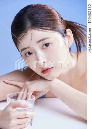 beauty concept photo of korean asain beautiful woman lying on her stomach with a glass cup 106402180