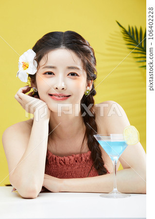 beauty concept photo of korean asain beautiful woman with flower in her hair and cocktail 106402228