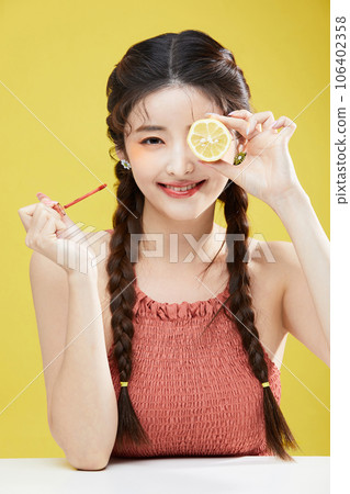 beauty concept photo of korean asain beautiful woman holding a lipgloss and a lemon beauty concept photo of korean asain beautiful woman holding a lipgloss and a lemon 106402358
