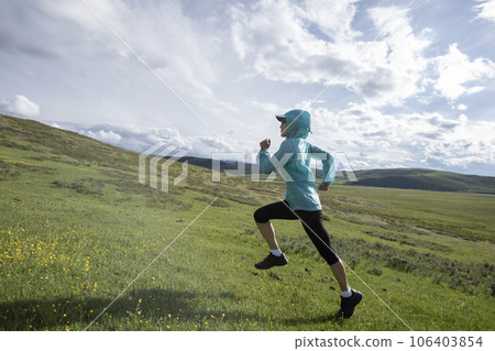 Woman trail runner cross country running at high altitude grassland Woman trail runner cross country running at high altitude grassland 106403854