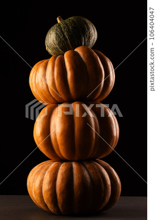 Orange and green pumpkins stacked up with copy space on black background 106404047
