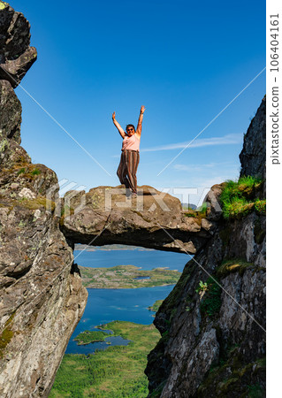 Active Senior tourist woman hiking at the beautiful Rock stuck in mountains Djevelporten. Norway Active Senior tourist woman hiking at the beautiful Rock stuck in mountains Djevelporten. Norway 106404161