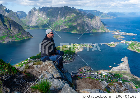 Relaxed happy hiker enjoys stunning views on Reinebringen peaks of Lofoten islands, fjords, Norway Relaxed happy hiker enjoys stunning views on Reinebringen peaks of Lofoten islands, fjords, Norway 106404165