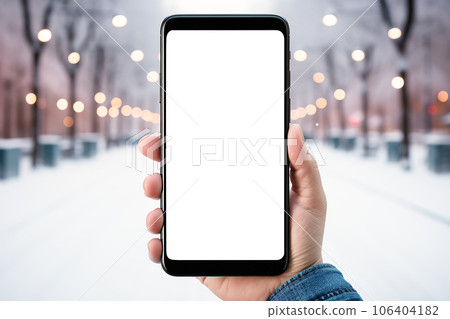 close-up smartphone in hand in winter evening day. smartphone with white empty display mockup 106404182