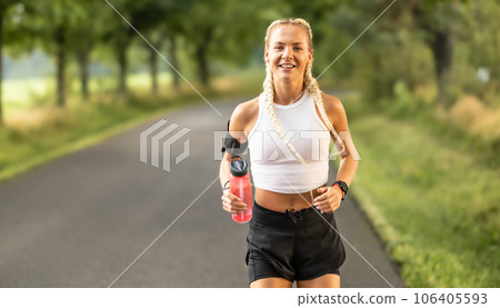 Female runner jogging outside in the park. Portrait of an athlete with a modern hairstyle 106405593