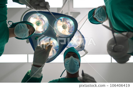 Gowned experts, lost amid the profound concentration amidst the intense surgical lights of a high-tech OR, diligently working toward the imminent miracle. 106406419
