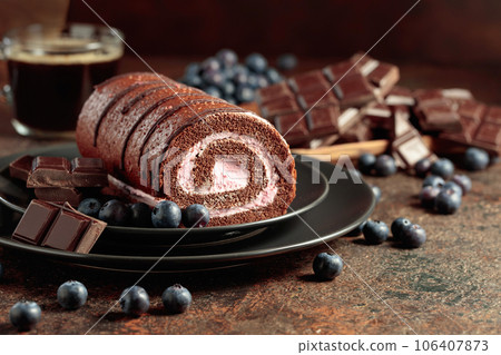 Chocolate roll cake with blueberries and a broken chocolate bar. 106407873