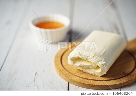 Close up picture of white cream milky kaymak butter roll poured with honey on wooden plate Close up picture of white cream milky kaymak butter roll poured with honey on wooden plate 106408204