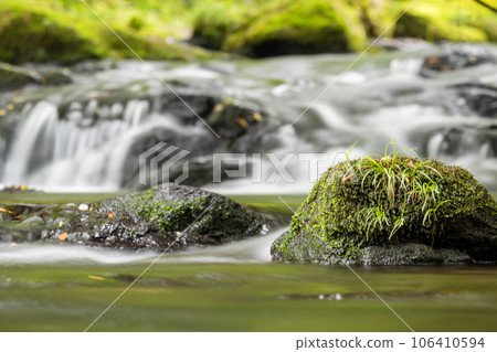 A waterfall leading to the Kikuchi Gorge with a clear stream flowing through nature 106410594
