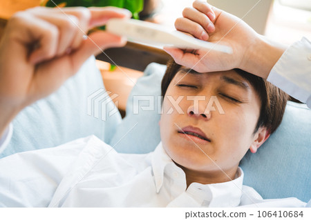 A man with a cold, a man with a fever and a thermometer 106410684
