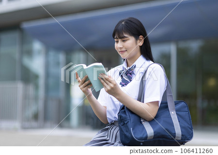 Student sitting on a bench and reading a book Student sitting on a bench and reading a book 106411260