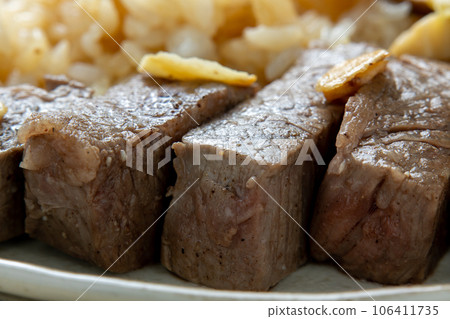 A close-up of a bite of steak. One plate with garlic rice. 106411735