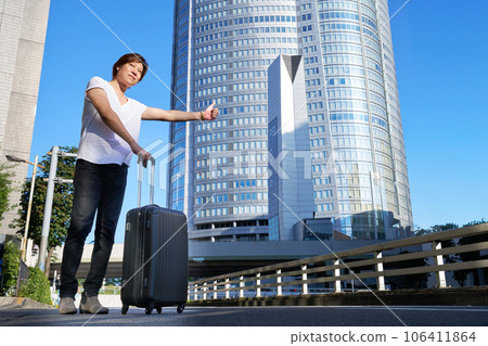 一個帶著手提箱的男人在街上招呼一輛車 106411864