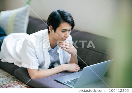 Young man relaxing at home using a computer Young man relaxing at home using a computer 106412293