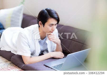 Young man relaxing at home using a computer Young man relaxing at home using a computer 106412294
