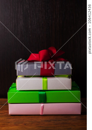 Colorful gift boxes with ribbon bows on a brown wooden background with copy space.Holidays,Christmas, New Year presents. Colorful gift boxes with ribbon bows on a brown wooden background with copy space.Holidays,Christmas, New Year presents. 106412436