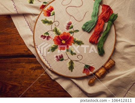 Flowers embroidery on white textile in hoop wooden background. Traditional ukrainian stitch embroidery motifs. Handmade 106412811