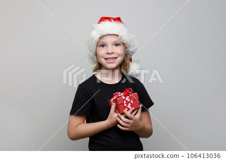Christmas kid girl in Santa hat holding red gift box on white background, Xmas portrait 106413036