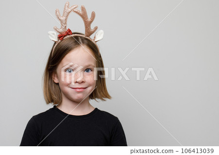 Christmas portrait of Happy child girl in Xmas hair band Santa's reindeer on white background Christmas portrait of Happy child girl in Xmas hair band Santa's reindeer on white background 106413039