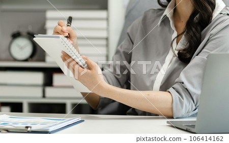 Businessman hand working at a tablet, computer and writing on a notepad with a pen in the office. on the wooden desk there a graph business diagram. Businessman hand working at a tablet, computer and writing on a notepad with a pen in the office. on the wooden desk there a graph business diagram. 106414162