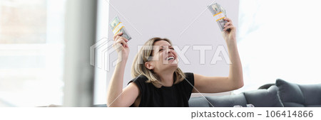 Happy smiling woman holding stacks of dollar bills and suitcase full of money on knees Happy smiling woman holding stacks of dollar bills and suitcase full of money on knees 106414866