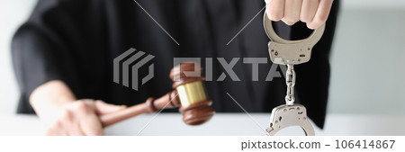 Judge with wooden gavel and holding handcuffs Judge with wooden gavel and holding handcuffs 106414867
