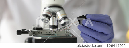 Chemist lab assistant looking at test sample using microscope 106414921