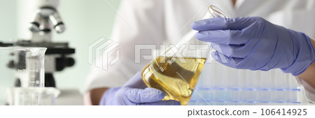 Scientist woman holding sample with yellow liquid 106414925