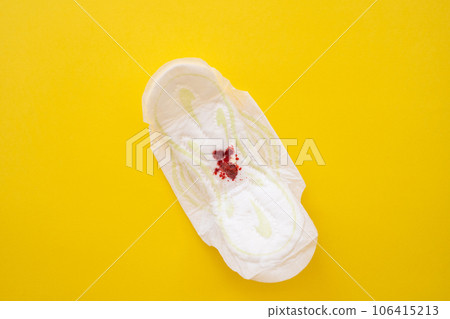 Women's sanitary pad with blood on a yellow background close-up 106415213