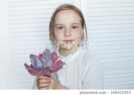 Cute child girl holding succulent flower rosette, studio portrait 106415953