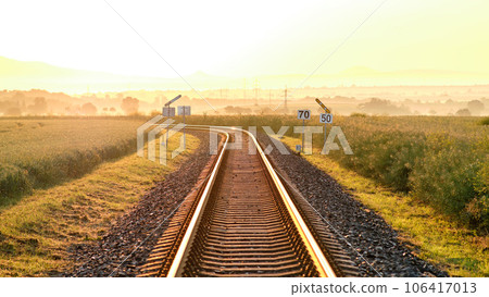 Railway tracks heading into distant golden bright sunlight. Summer vacation rail road trip concept. Czech Republic, Europe. 106417013