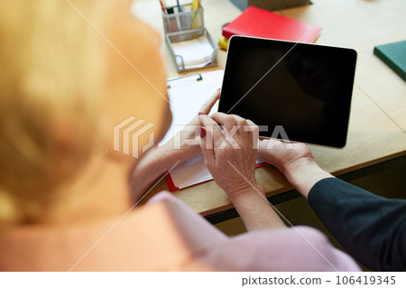 Close-up image of mature, old woman using tablet at work. Modern technologies in professional sphere. 106419345