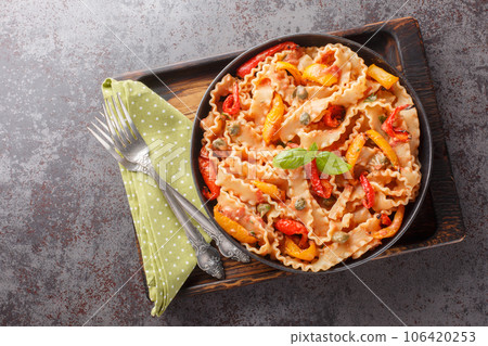 Reginette Pasta With Bell Peppers and Basil in Creamy Tomato Sauce with capers closeup on the plate. Horizontal top view Reginette Pasta With Bell Peppers and Basil in Creamy Tomato Sauce with capers closeup on the plate. Horizontal top view 106420253