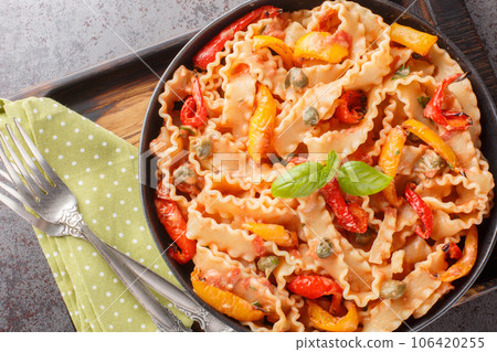Ribbon-shaped Italian pasta mafaldine cooked with creamy tomato sauce and bell peppers close-up in a bowl. horizontal top view 106420255