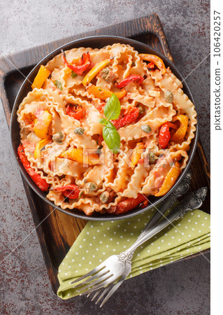 Mafalda Pasta in Creamy Tomato Sauce with capers and baked papper closeup on the plat. Vertical top view 106420257