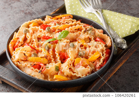Ribbon-shaped Italian pasta mafaldine cooked with creamy tomato sauce and bell peppers close-up in a bowl. horizontal 106420261