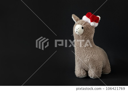 Toy lama in Christmas Santa hat black background. Copyspace. Toy lama in Christmas Santa hat black background. Copyspace. 106421769