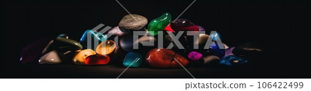 A pile of colorful stones on a black background, AI 106422499