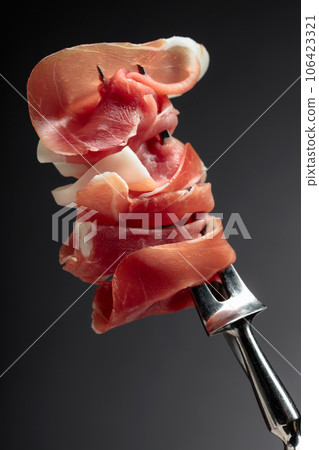 Slices of prosciutto on a fork. 106423321