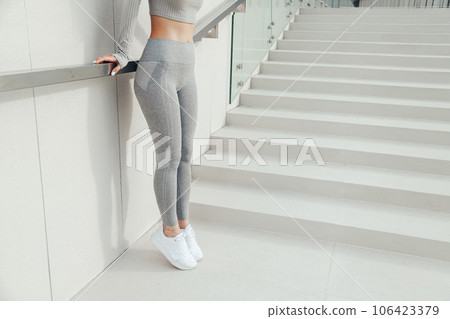 Fitness woman legs in grey workout leggings and white sneakers posing outdoors 106423379