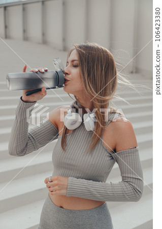 Fitness woman drinking water outdoors 106423380
