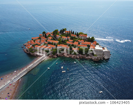Aerial view of Sveti Stefan island and shore in a beautiful summer day, Montenegro from flying drone. Panoramic above view of Saint Stephen luxury resort. Tourism and leisure concept. Aero photography Aerial view of Sveti Stefan island and shore in a beautiful summer day, Montenegro from flying drone. Panoramic above view of Saint Stephen luxury resort. Tourism and leisure concept. Aero photography 106423405