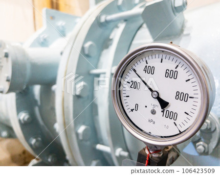 Closeup of the large dial gauge on the water pipe. 106423509