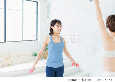 A young woman training with a dumbbell 106423863