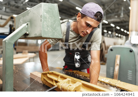 Young carpenter working on woodworking machines in the furniture factory 106424941