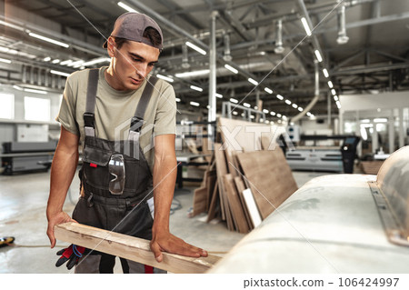 Male carpenter using some woodworking tools for his work in a factory 106424997