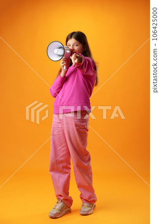 Teen girl making announcement with megaphone on yellow background Teen girl making announcement with megaphone on yellow background 106425000