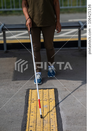 Close-up of the legs of an elderly blind woman at a bus stop. Close-up of the legs of an elderly blind woman at a bus stop. 106425136