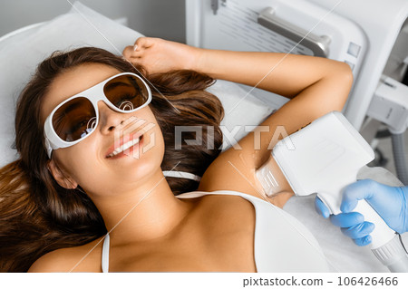 Hair removal from armpits for smiling brunette in a beauty salon. Hair removal from armpits for smiling brunette in a beauty salon. 106426466
