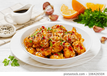 crispy orange cauliflower florets in white bowl 106426504
